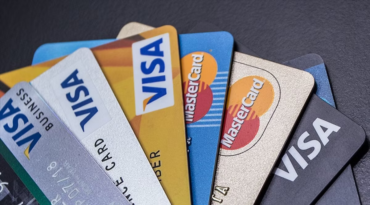 Fanned Visa and Mastercard credit cards on a dark surface, showing blue, gold, silver, and black card designs.
