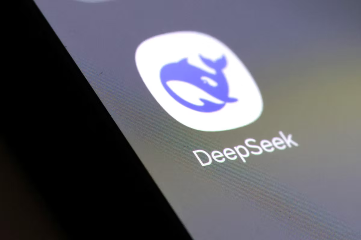 App icon on screen: blue whale logo with "DeepSeek" text beneath on a digital display. Dark edges suggest a close-up view.