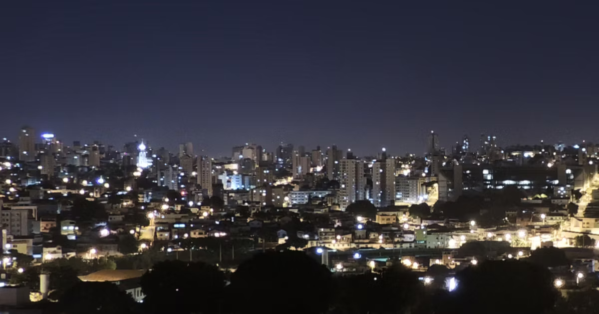 A sprawling city skyline at night, lit windows and street lights running to the horizon under a dark blue sky.