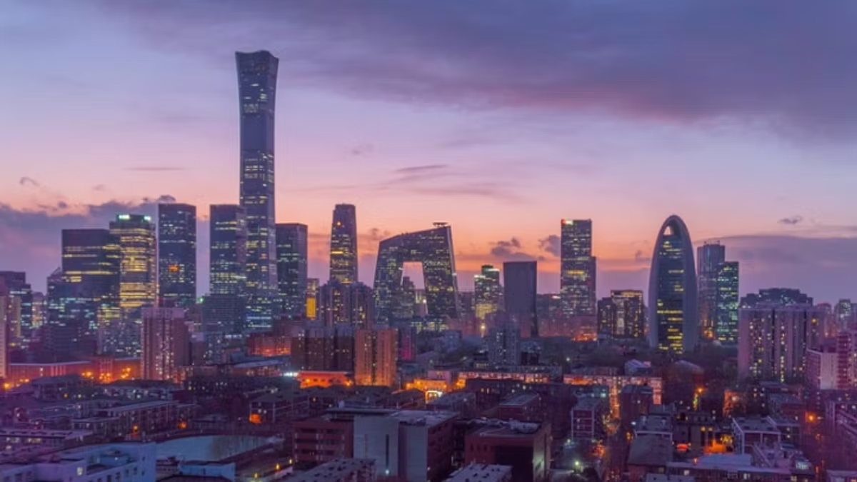 The Beijing central business district skyline at dusk, distinctive towers silhouetted against a purple and orange sky.