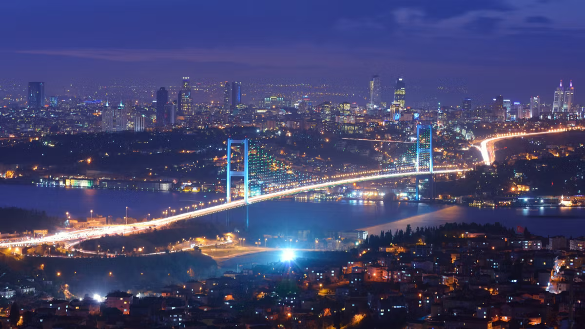 Istanbul at night from above, the illuminated Bosphorus Bridge spanning the water with the city lit on both banks.