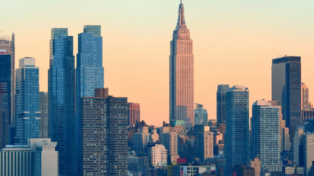 The Midtown Manhattan skyline at sunset, the Empire State Building rising above surrounding towers against a peach sky.