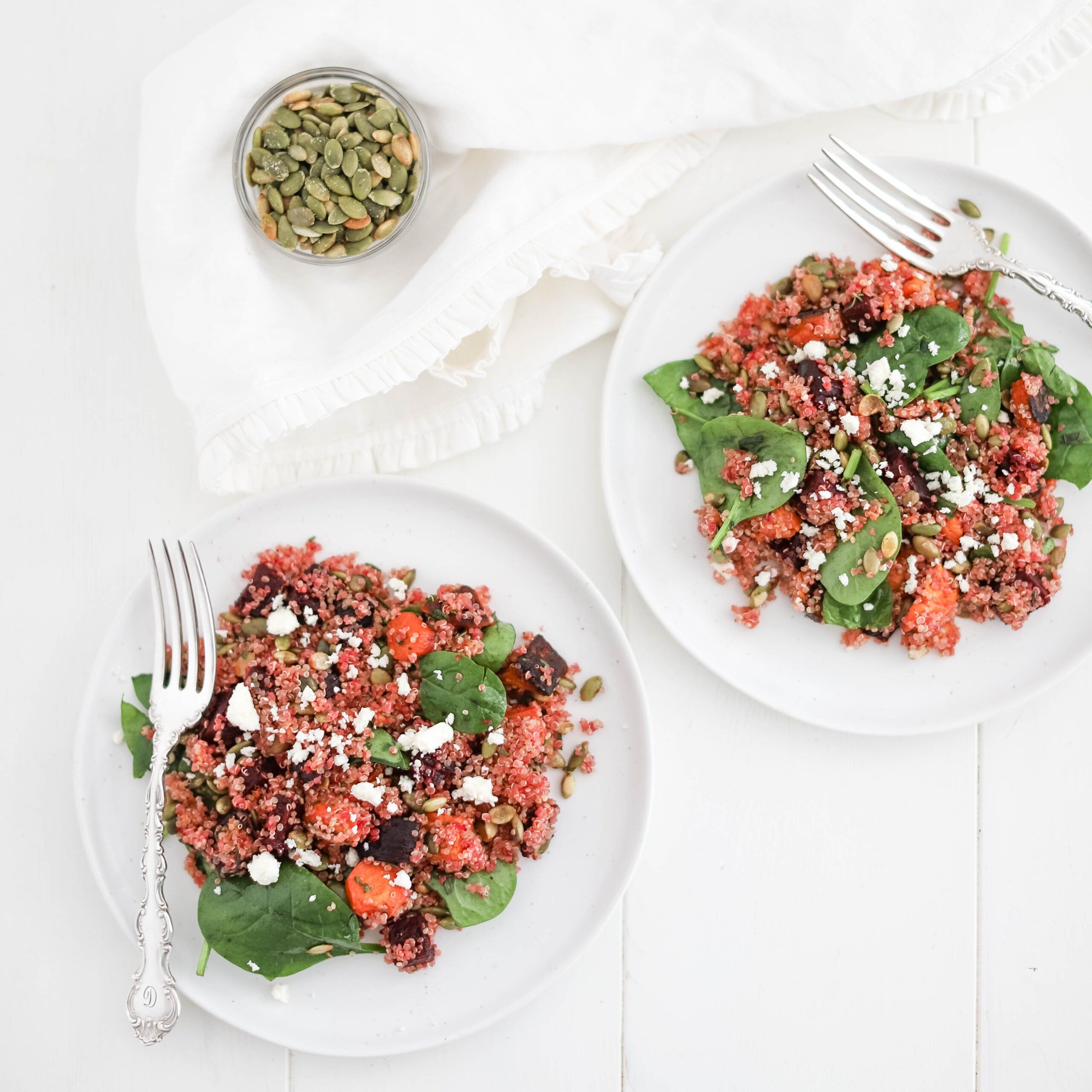 quinoa salad on spinach and a white plate