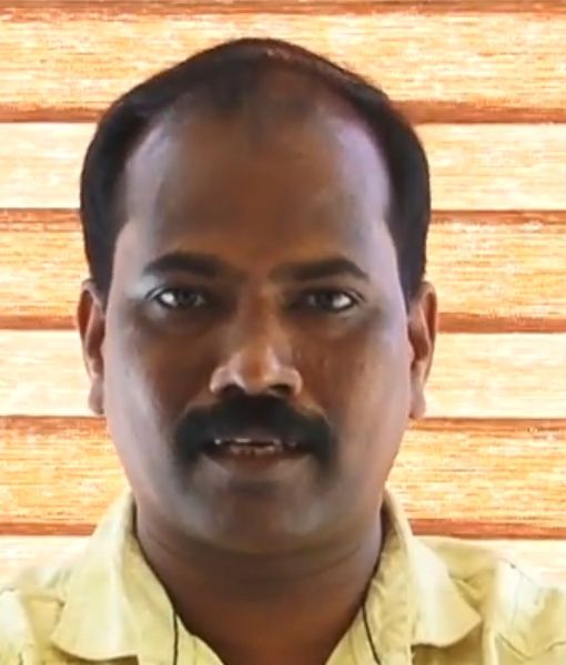 Ajith Poojappura with a moustache in a pale yellow shirt, facing the camera