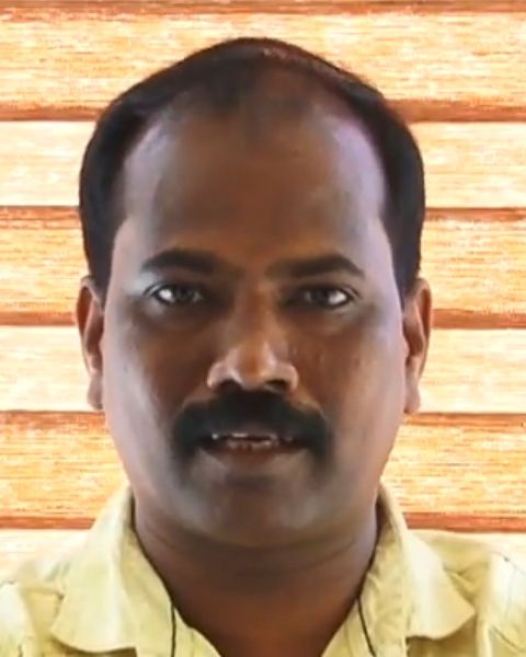 Ajith Poojappura with a moustache in a pale yellow shirt, facing the camera