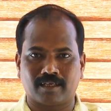 Ajith Poojappura with a moustache in a pale yellow shirt, facing the camera