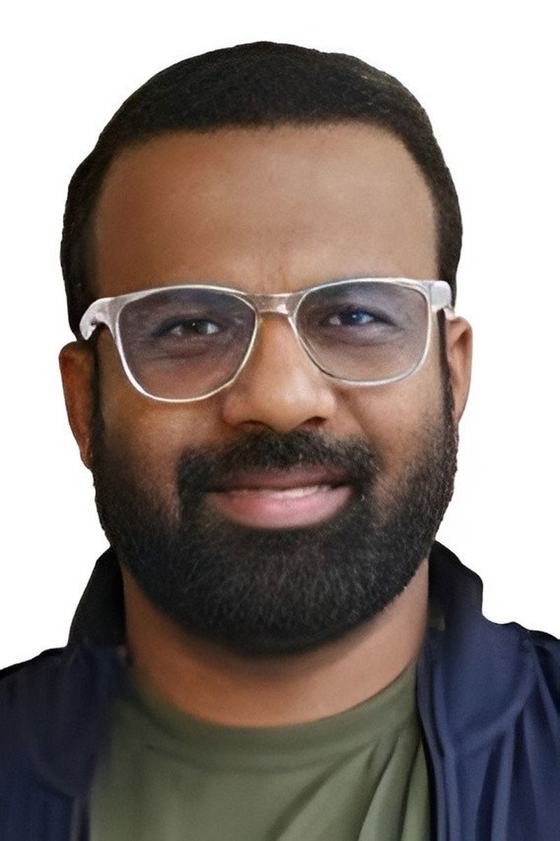 Jakes Bejoy in clear-framed glasses with a beard, close-up portrait