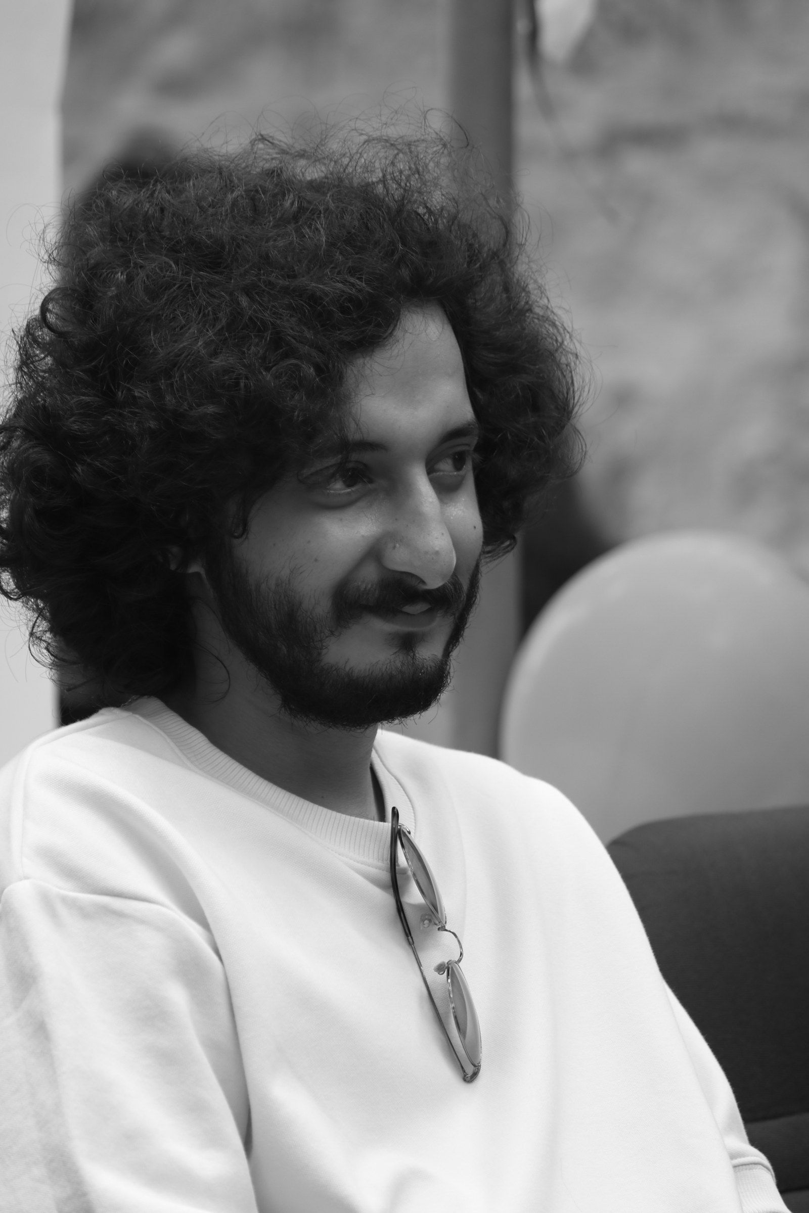 Sushin Shyam smiling in a white T-shirt, black-and-white photo