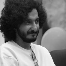 Sushin Shyam smiling in a white T-shirt, black-and-white photo