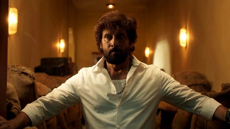 Vikram stands with arms outstretched in a corridor in the Power House title promo