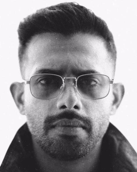 Arjun Ashokan in clear-framed glasses and a dark jacket, black-and-white portrait