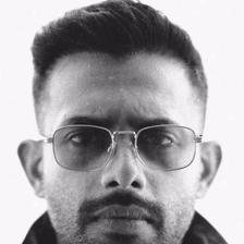 Arjun Ashokan in clear-framed glasses and a dark jacket, black-and-white portrait