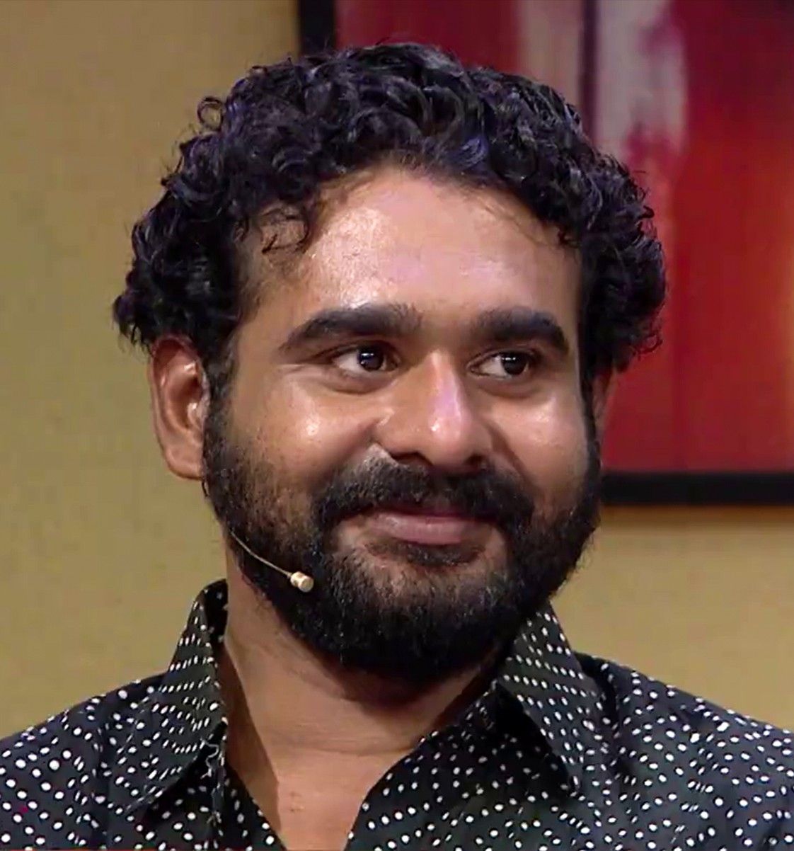 Sidharth Bharathan with curly hair and a beard at an event