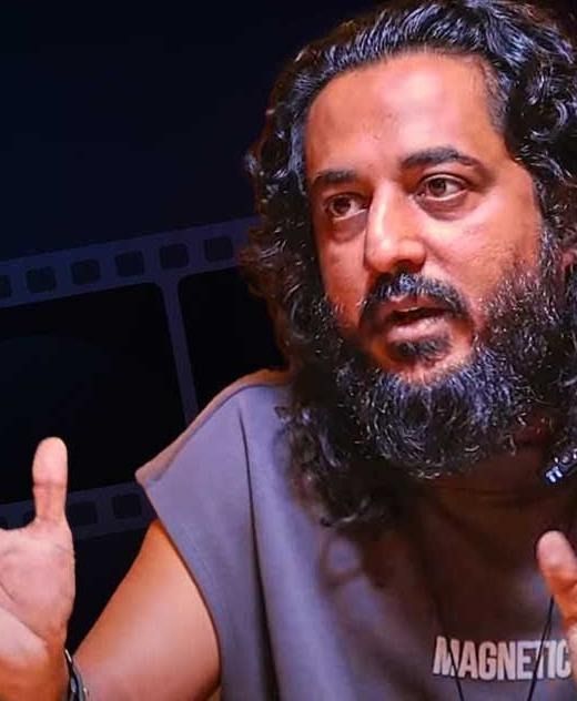 Sajid Yahiya with long hair and a beard, mid-conversation portrait