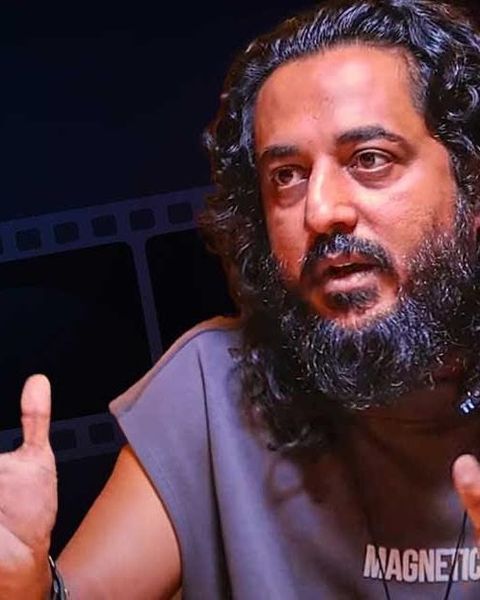 Sajid Yahiya with long hair and a beard, mid-conversation portrait