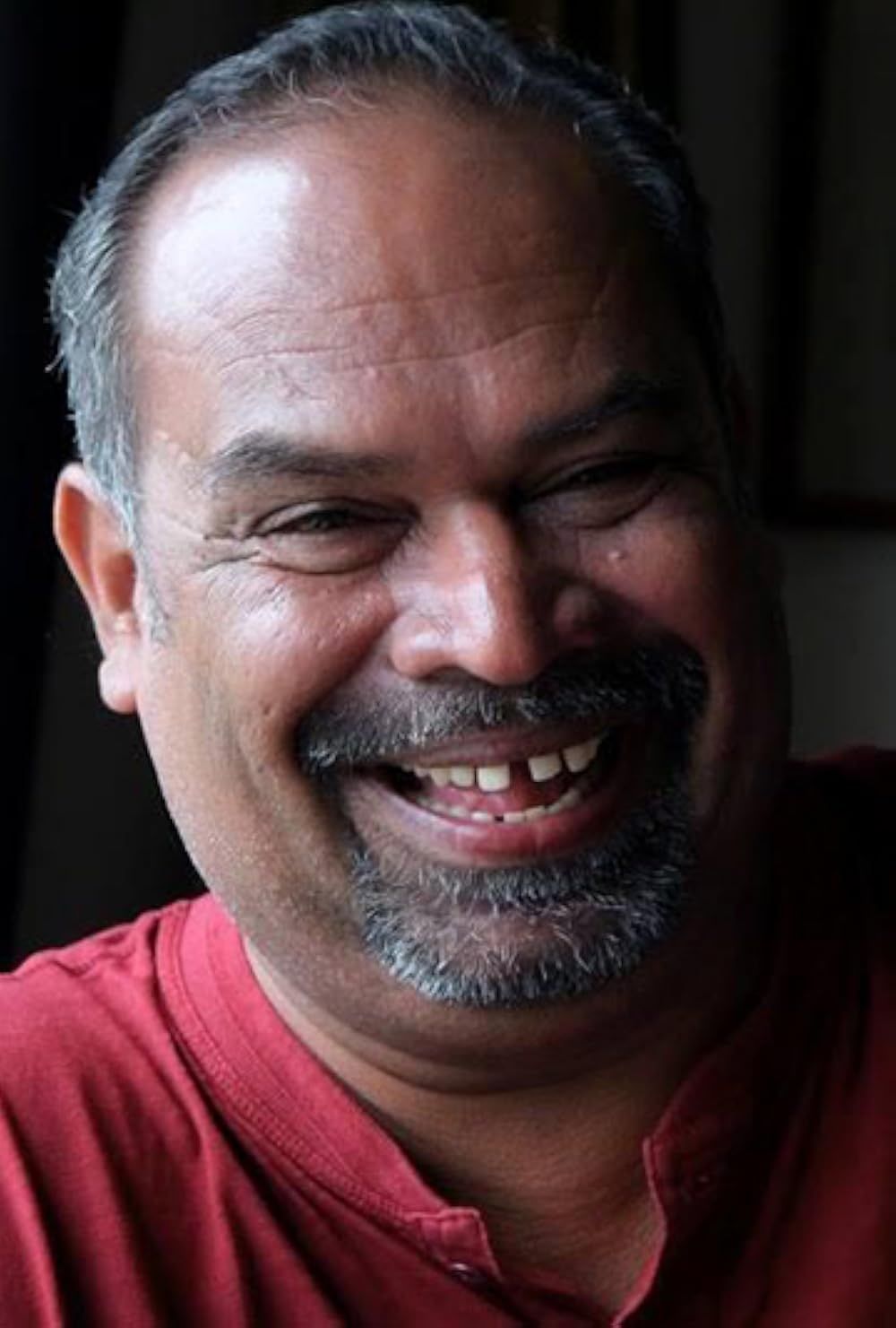 Alencier Ley Lopez in a red shirt, laughing, close portrait