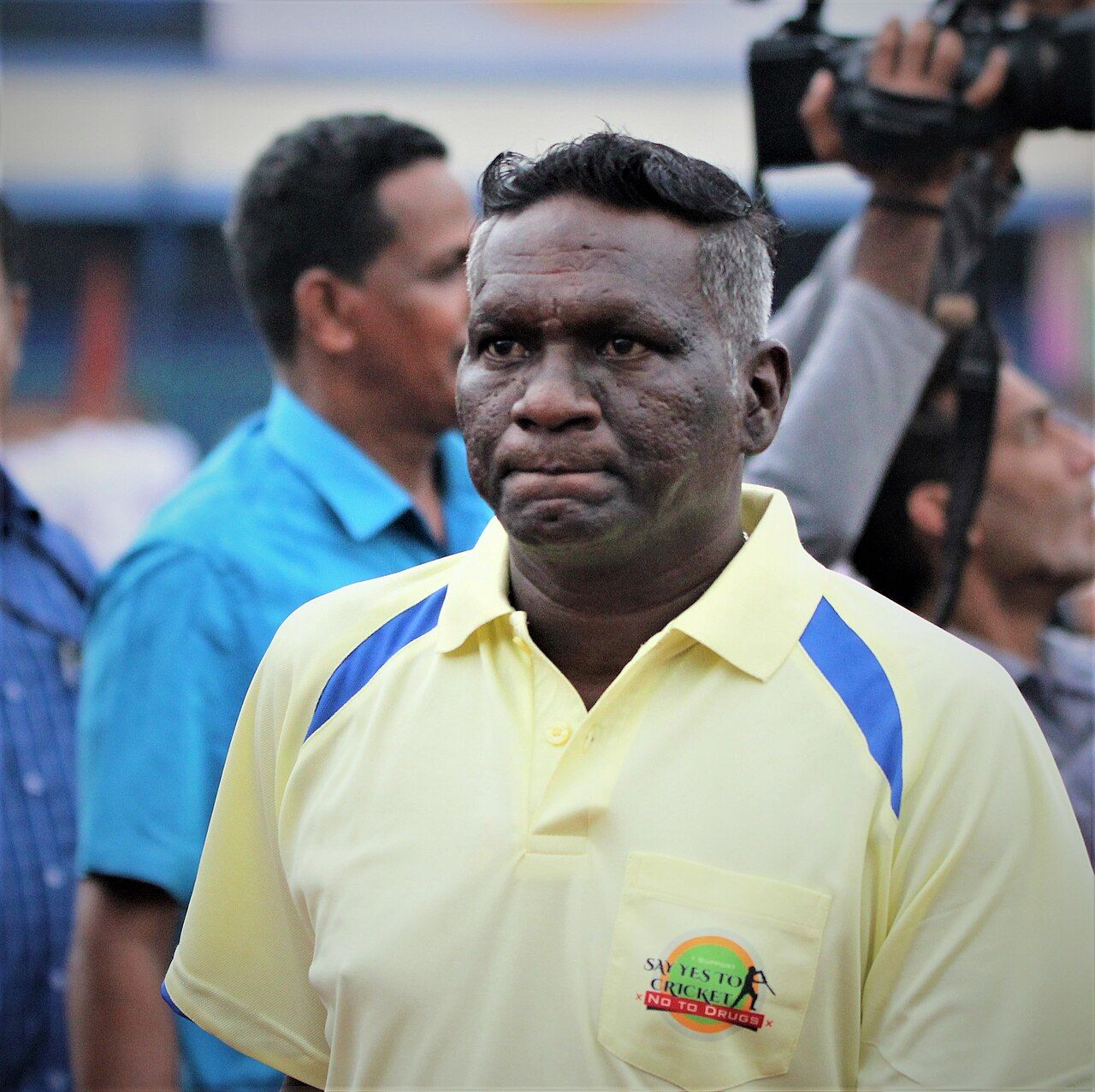 I. M. Vijayan in a yellow polo shirt among people outdoors