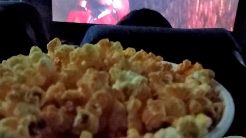 A tub of popcorn in front of a cinema screen