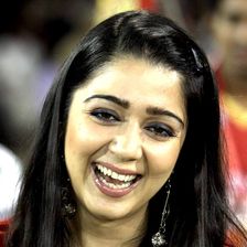Charmme Kaur laughing in a red and yellow jersey at a stadium