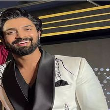 Dev Mohan smiling in a white jacket with black lapels