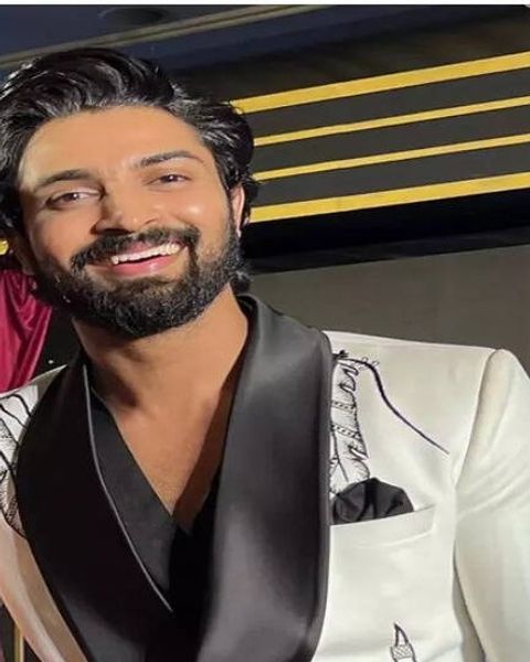 Dev Mohan smiling in a white jacket with black lapels
