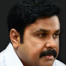 Dileep with a moustache in a white shirt, close-up portrait