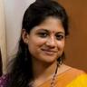 Aditi Balan smiling in a yellow and orange saree with a red bindi and dangling earrings, close-up portrait