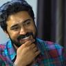 Nivin Pauly smiling with his hand on his chin, portrait