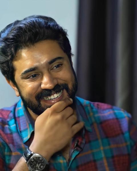 Nivin Pauly smiling with his hand on his chin, portrait