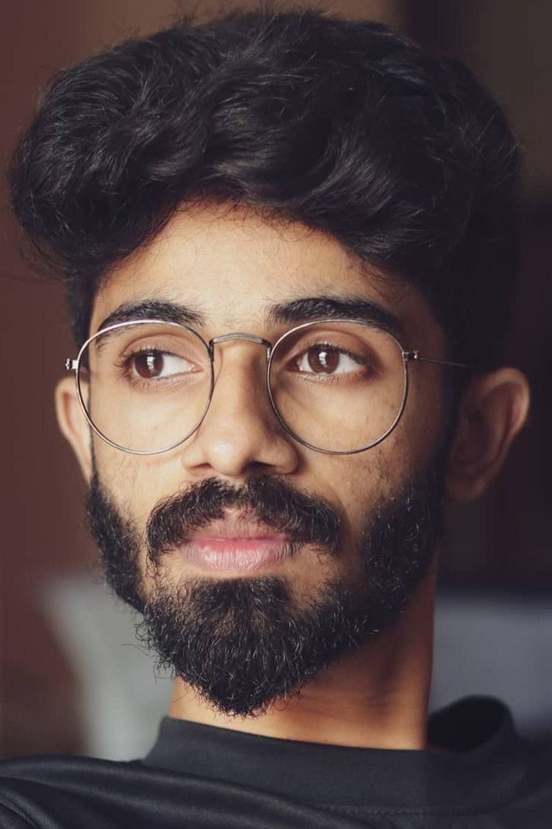 Anand Menen with glasses and a beard, close-up portrait