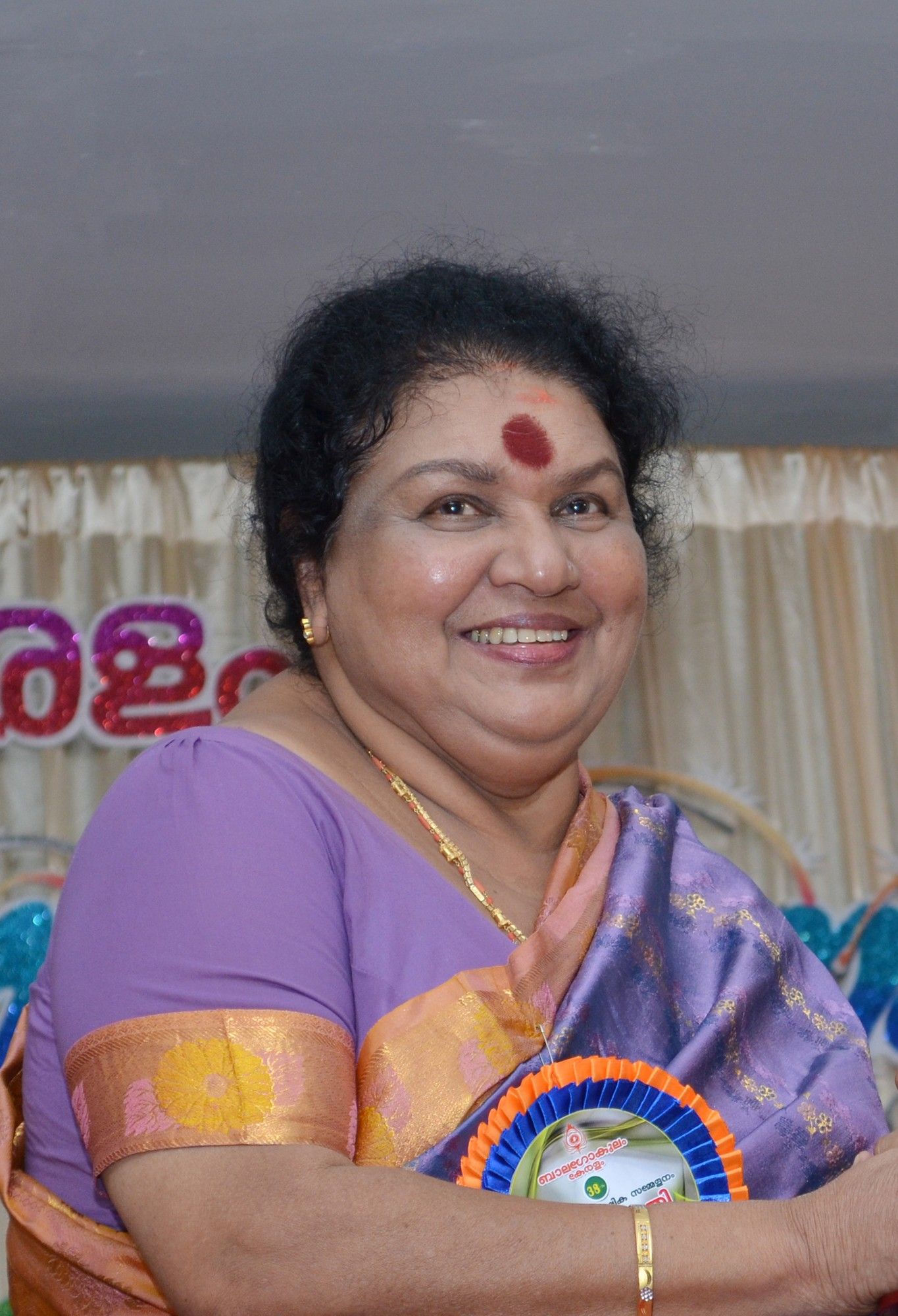 Kaviyoor Ponnamma smiling in a purple saree at an event