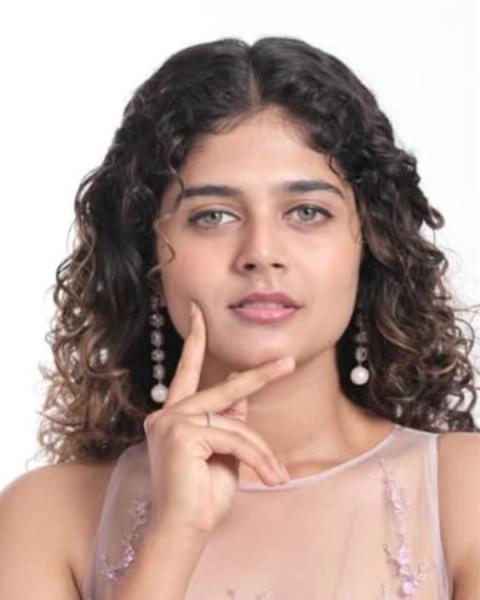 Aiswarya Raj with curly hair resting her chin on her hand