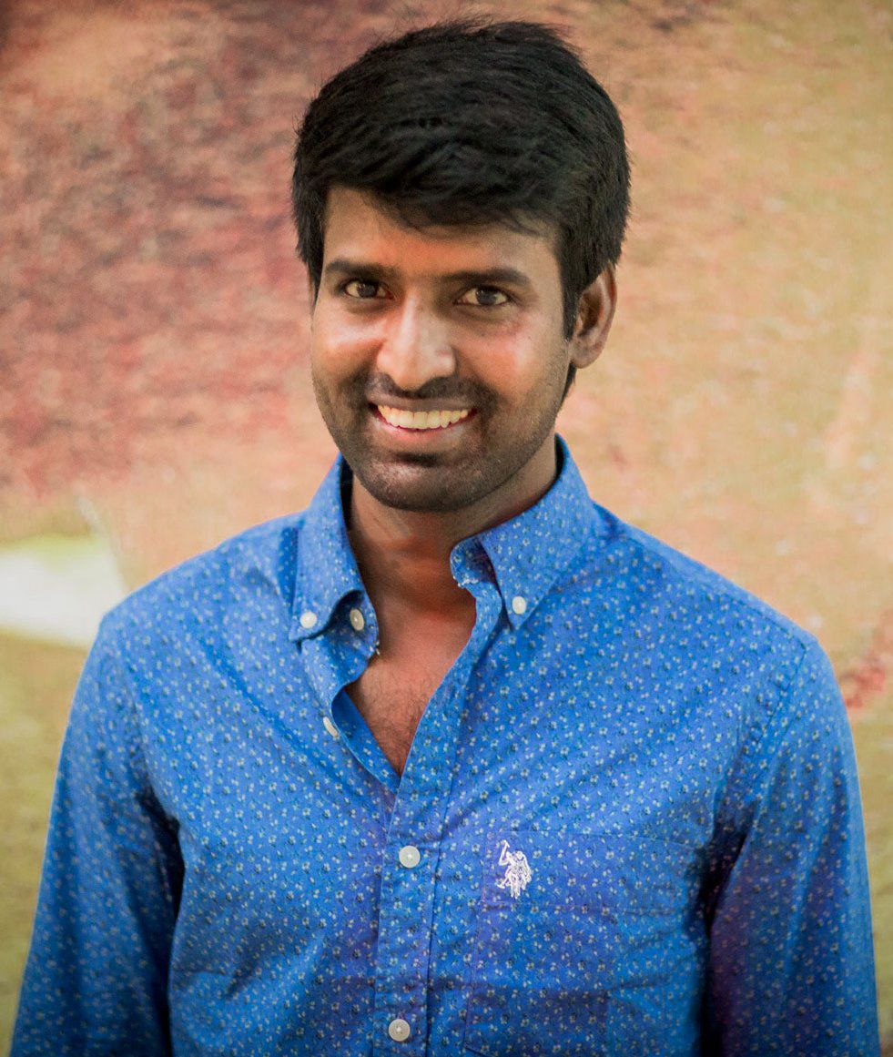 Soori smiling in a blue shirt, half-length portrait