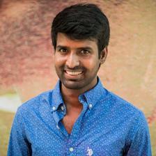 Soori smiling in a blue shirt, half-length portrait