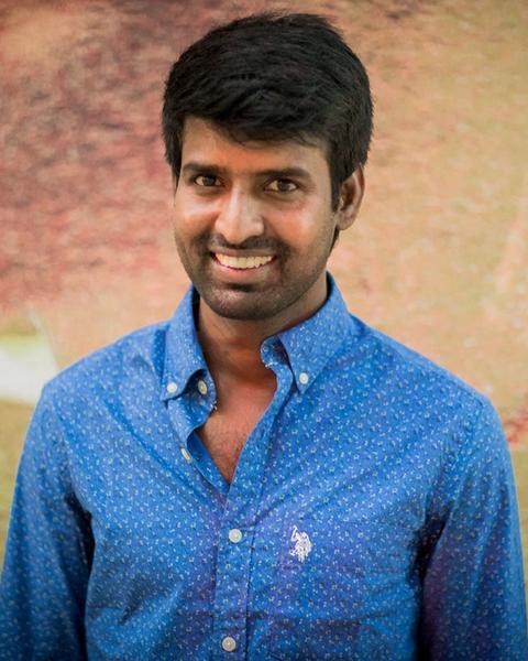 Soori smiling in a blue shirt, half-length portrait