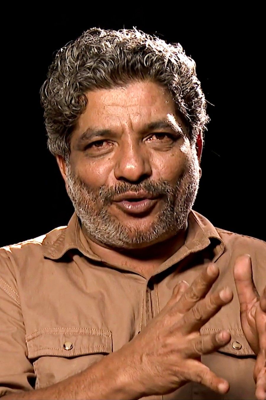 Jaffer Idukki with grey curly hair and a moustache in a khaki shirt, portrait