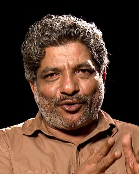 Jaffer Idukki with grey curly hair and a moustache in a khaki shirt, portrait