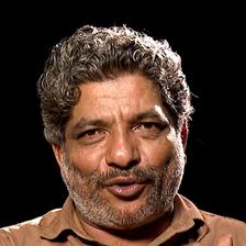 Jaffer Idukki with grey curly hair and a moustache in a khaki shirt, portrait