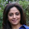 Nadia Moidu smiling in a blue shirt outdoors, portrait