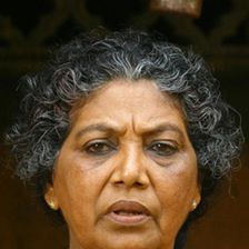 Santhakumari with curly grey hair and a black necklace, close-up
