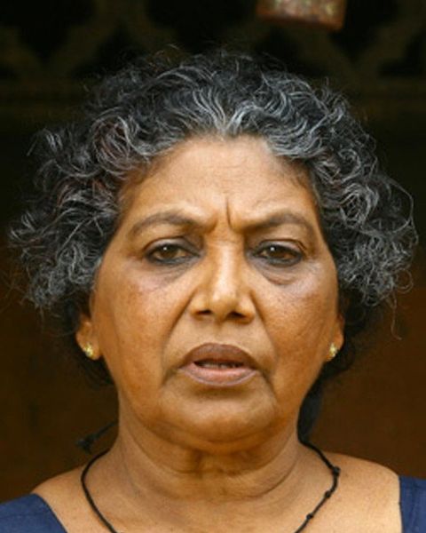 Santhakumari with curly grey hair and a black necklace, close-up