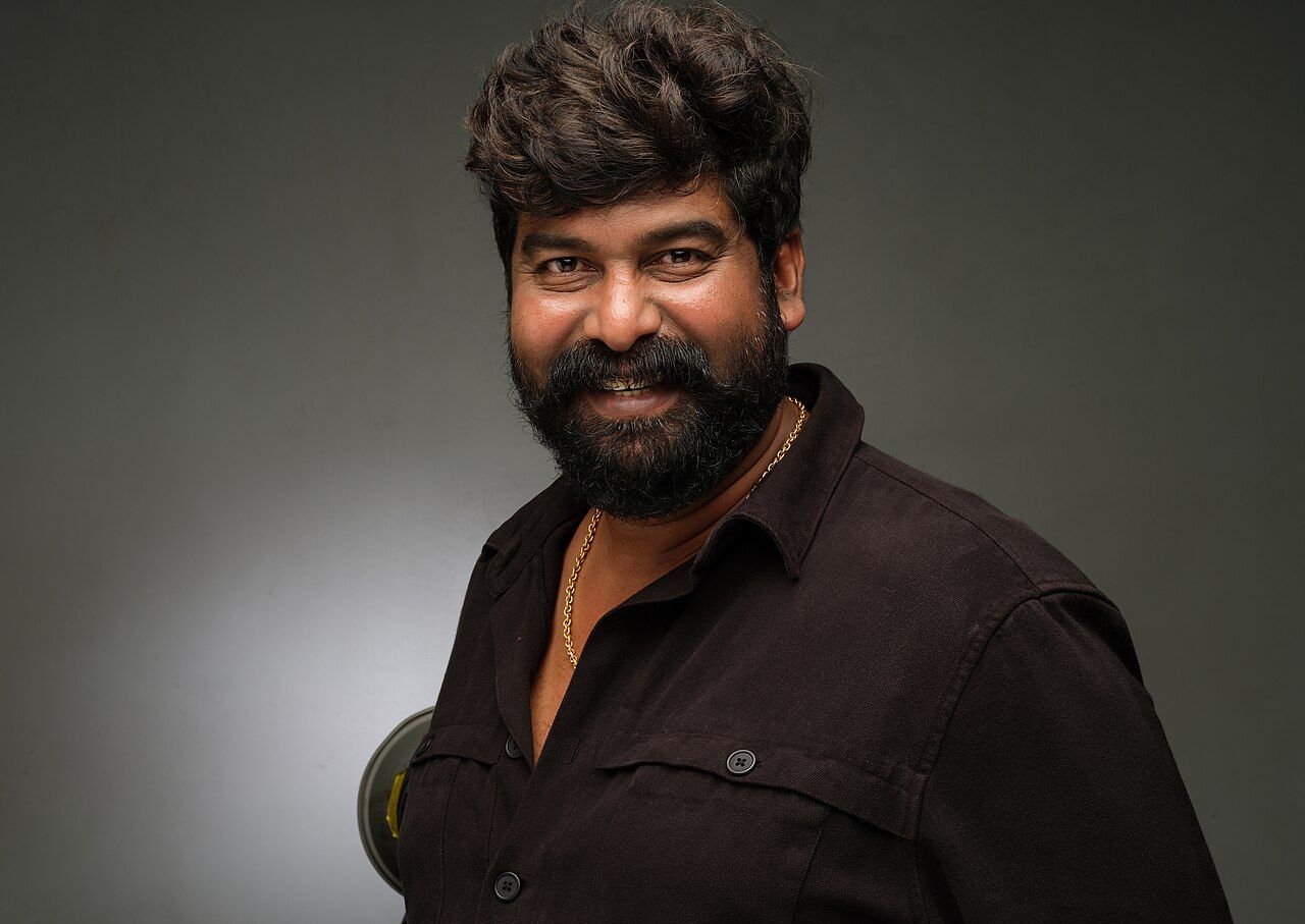 Joju George with a beard in a dark shirt, studio portrait