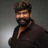Joju George with a beard in a dark shirt, studio portrait