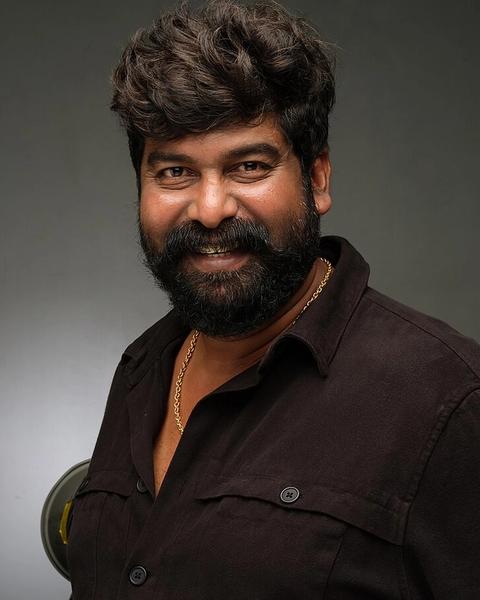 Joju George with a beard in a dark shirt, studio portrait
