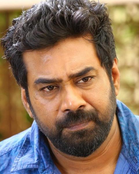 Biju Menon with a beard in a blue shirt, close-up portrait