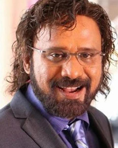 Rafi with glasses and a beard in a dark suit, smiling