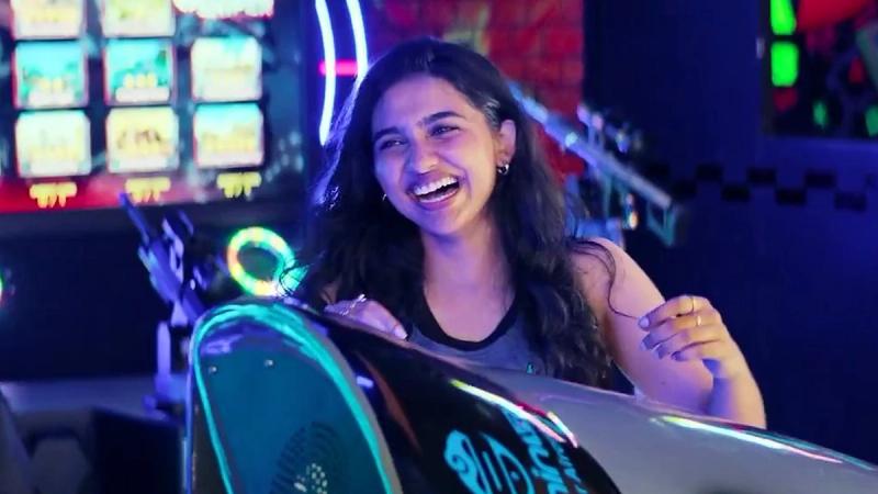Mamitha Baiju laughing at an arcade game in a scene from Dude
