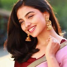Mamitha Baiju smiling in a pink saree with gold earrings