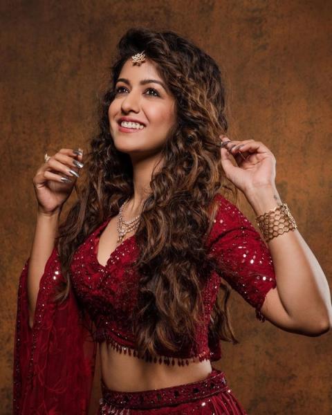 Ishita Dutta posing in a red sequinned outfit with long wavy hair