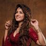 Ishita Dutta posing in a red sequinned outfit with long wavy hair